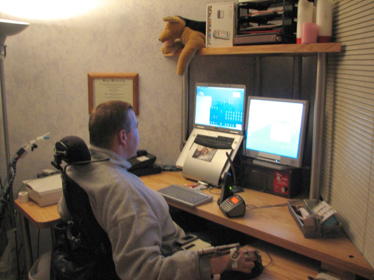 Quadriplegic in wheelchair using Maverick Corner Wheelchair Desk with  high monitor Shelf